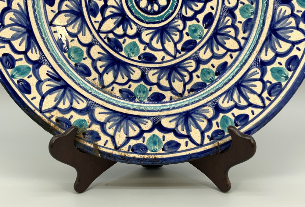 A large round tin-glazed earthenware charger plate featuring concentric hand-painted Moorish floral motifs in cobalt blue and turquoise on a cream ground. View VII