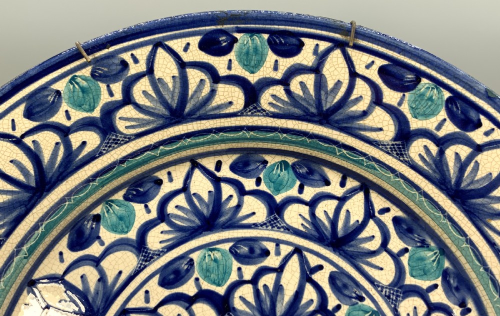 A large round tin-glazed earthenware charger plate featuring concentric hand-painted Moorish floral motifs in cobalt blue and turquoise on a cream ground. View IX