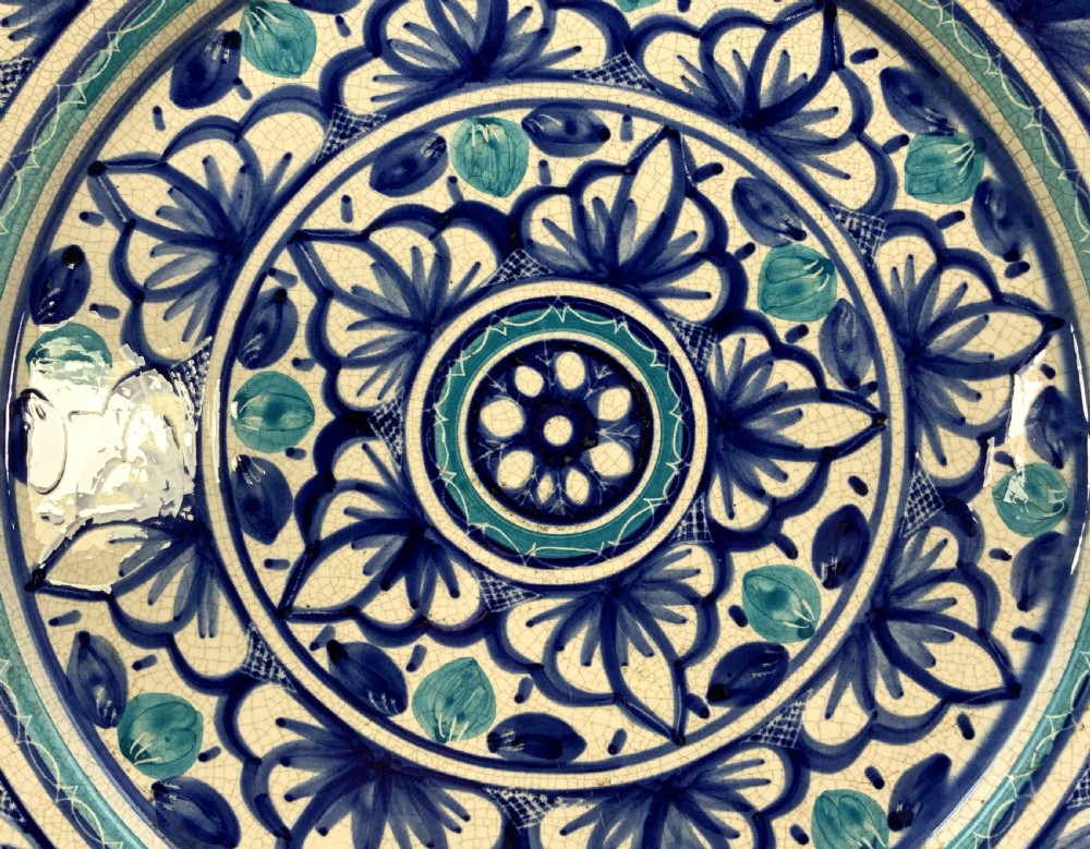 A large round tin-glazed earthenware charger plate featuring concentric hand-painted Moorish floral motifs in cobalt blue and turquoise on a cream ground. View X