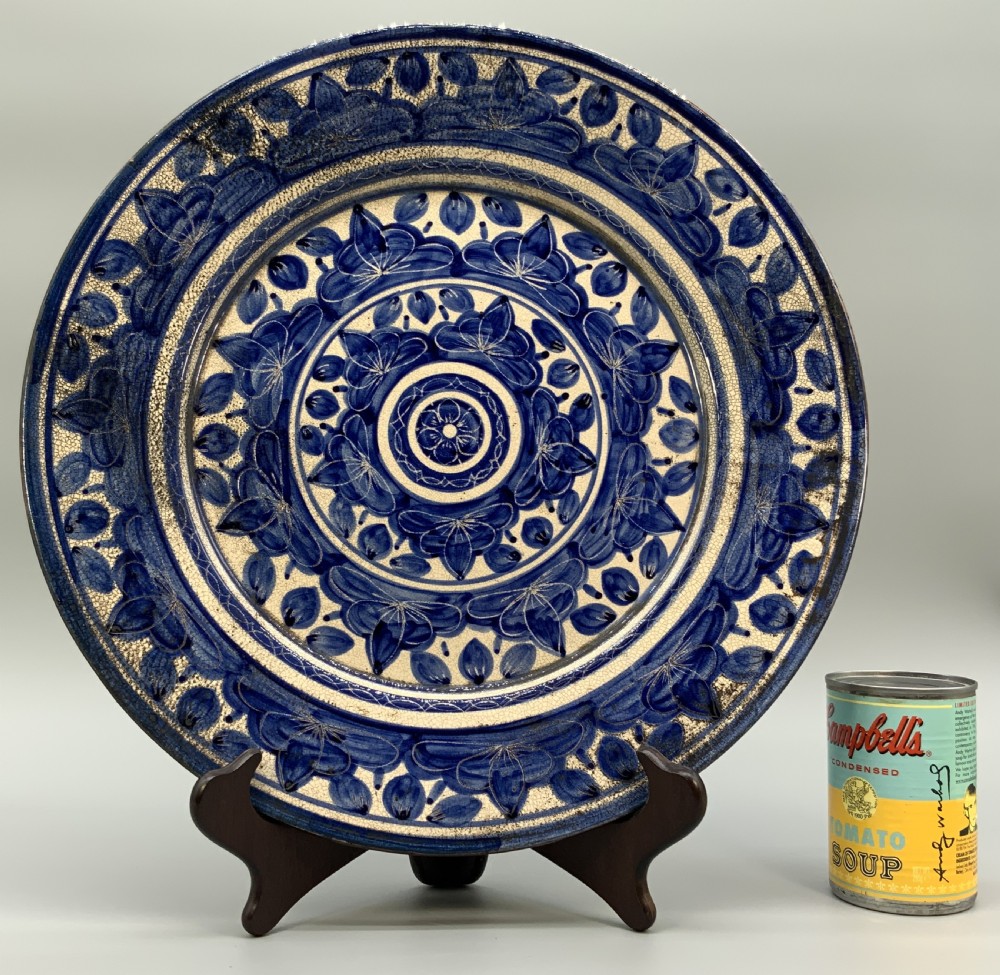 A circular blue and cream tin-glazed earthenware charger plate featuring hand-painted Moorish floral motifs and fine glaze crazing. View III