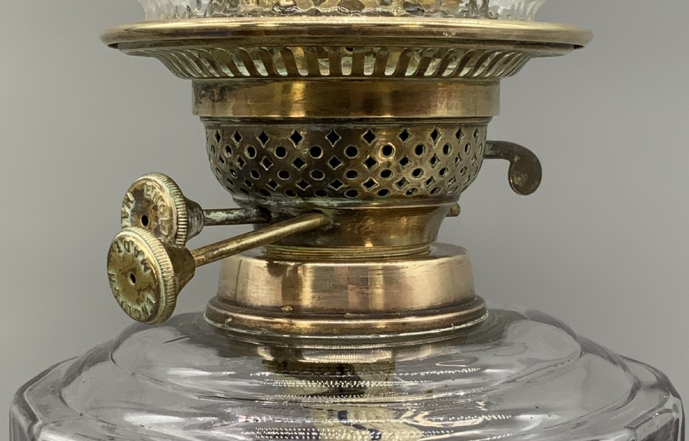 An Art Nouveau table oil lamp featuring a black ceramic base, cast brass stem, clear glass reservoir, double wick burner, clear chimney, and ruffled glass shade. View V