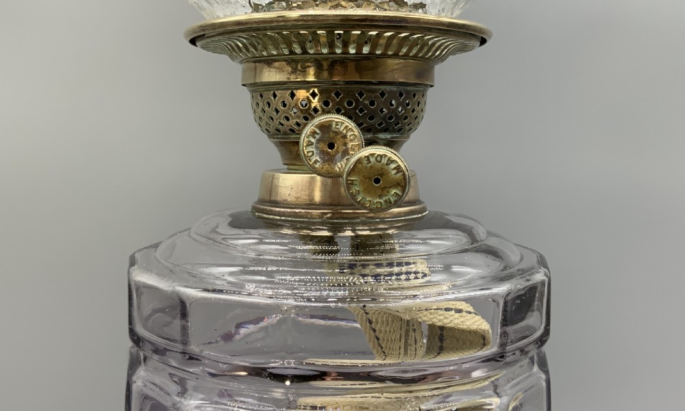 An Art Nouveau table oil lamp featuring a black ceramic base, cast brass stem, clear glass reservoir, double wick burner, clear chimney, and ruffled glass shade. View IX