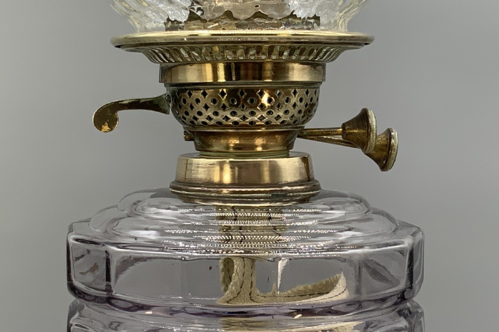 An Art Nouveau table oil lamp featuring a black ceramic base, cast brass stem, clear glass reservoir, double wick burner, clear chimney, and ruffled glass shade. View X