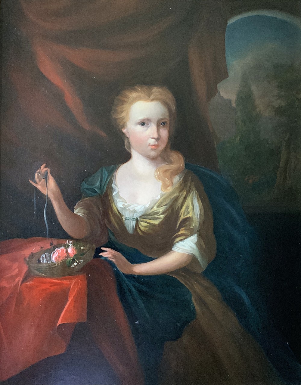 An antique oil painting depicting a seated woman beside a basket of flowers on a draped table, set within a gilded wooden frame. View II