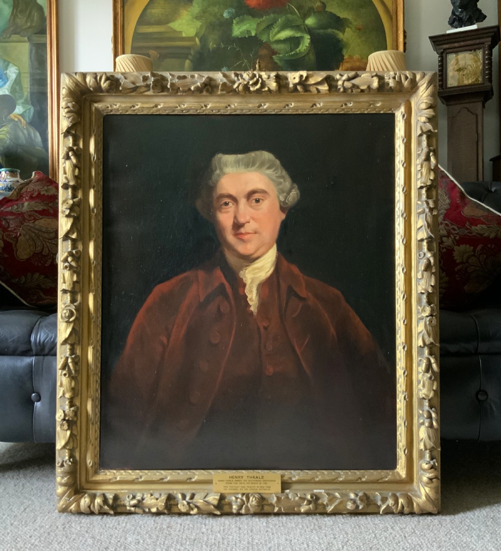 An oil portrait painting depicting an 18th-century gentleman in a burgundy coat and white cravat, set inside an ornate giltwood frame. View II