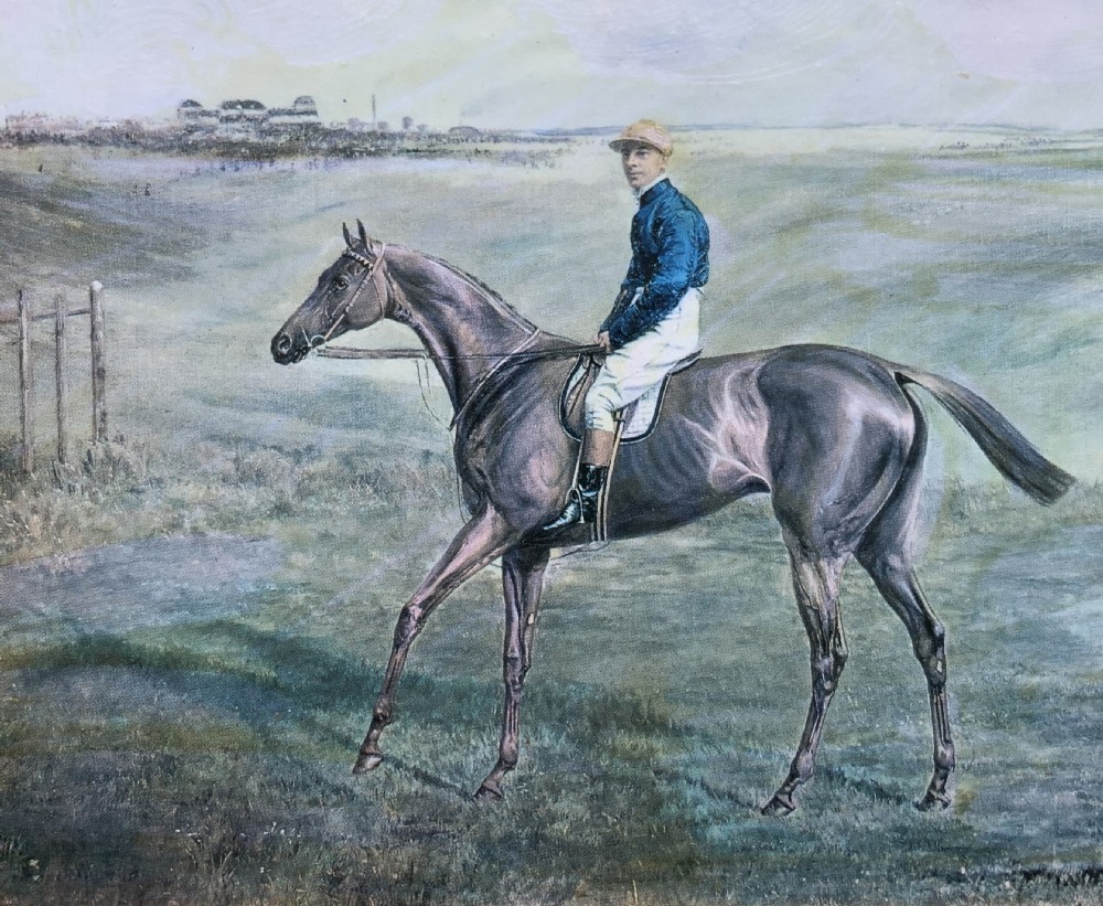 A framed miniature print depicting a jockey in blue silks seated on a dark racehorse in a countryside landscape, enclosed in a moulded timber frame with a gold inner slip. View IV