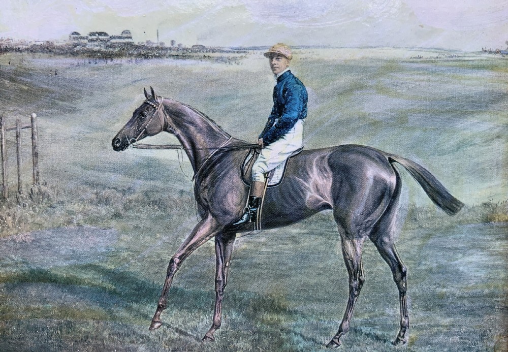 A framed miniature print depicting a jockey in blue silks seated on a dark racehorse in a countryside landscape, enclosed in a moulded timber frame with a gold inner slip. View V