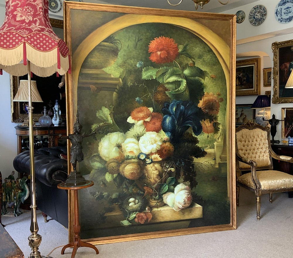 A monumental oil painting depicting a detailed floral arrangement in a stone classical urn set within an architectural stone arch.
