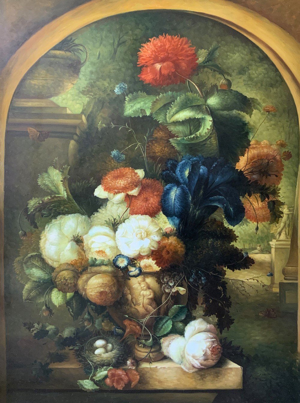 A monumental oil painting depicting a detailed floral arrangement in a stone classical urn set within an architectural stone arch. View II