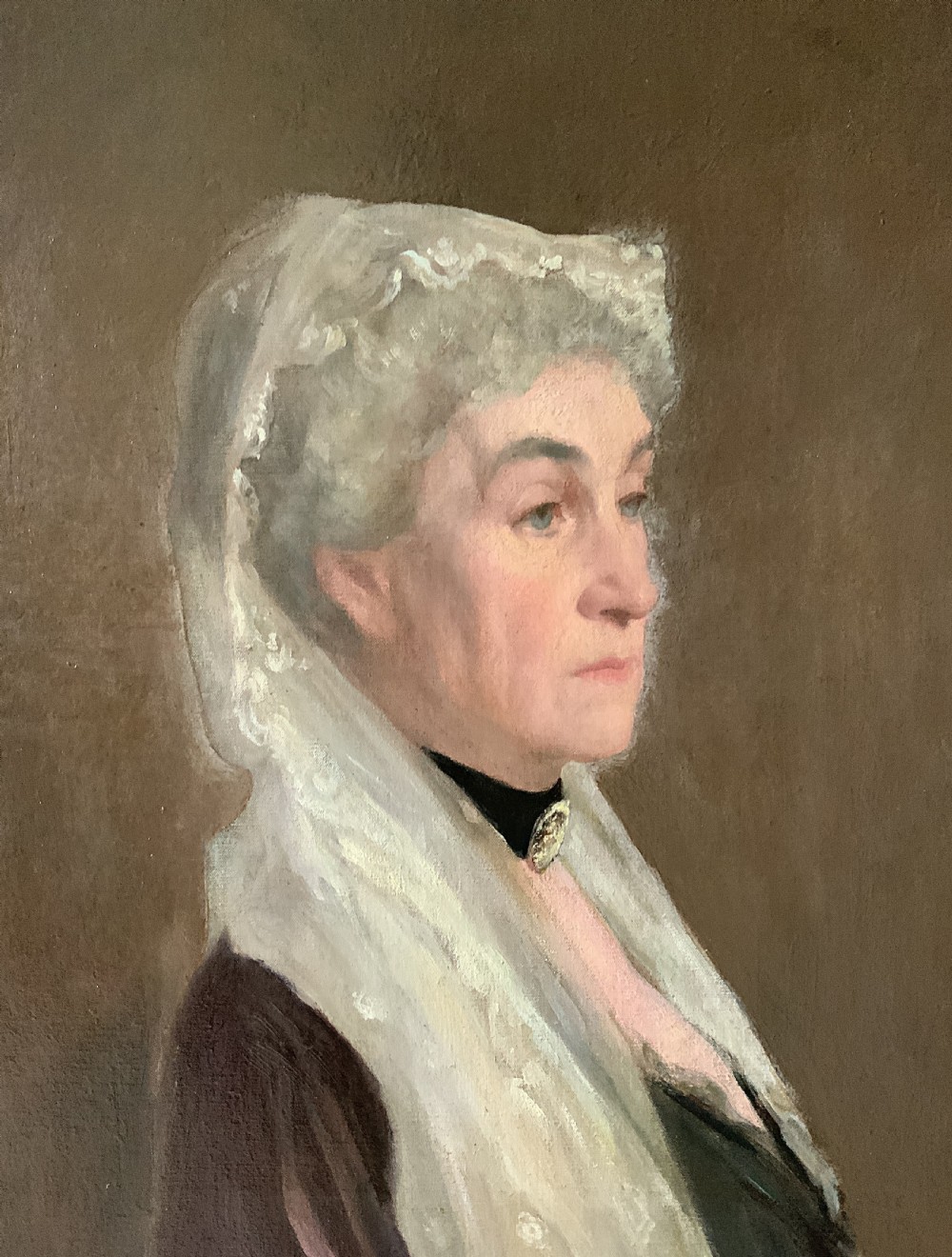 A large framed oil portrait painting on canvas depicting a mature woman wearing a lace head covering and draped red shawl against a dark brown background. View VIII