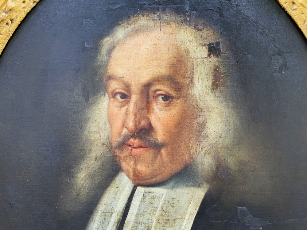 A seventeenth-century oval oil portrait of a gentleman with grey hair wearing a black coat and white collar, housed in a carved gold leaf frame. View III