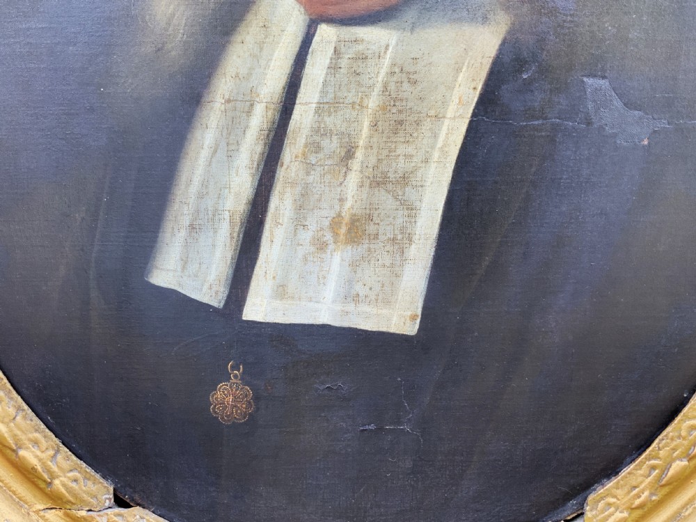 A seventeenth-century oval oil portrait of a gentleman with grey hair wearing a black coat and white collar, housed in a carved gold leaf frame. View V