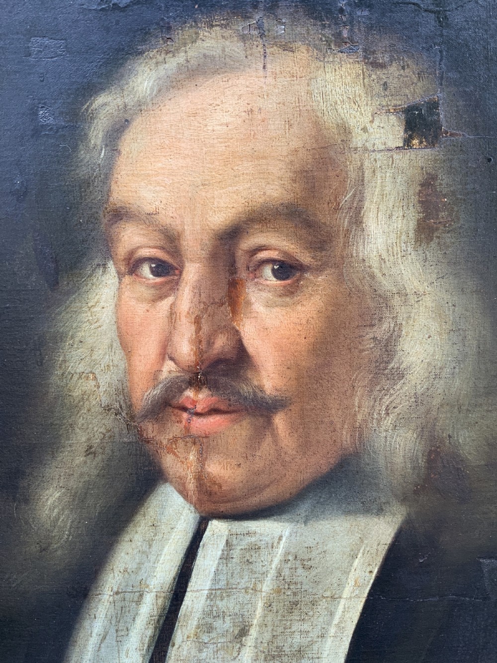 A seventeenth-century oval oil portrait of a gentleman with grey hair wearing a black coat and white collar, housed in a carved gold leaf frame. View VII
