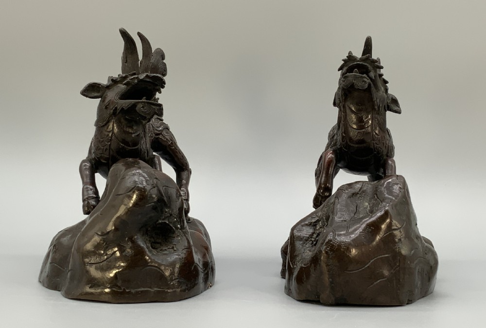 A pair of patinated dark bronze Japanese mythical creature statues positioned on sculpted rocky bases. View VI
