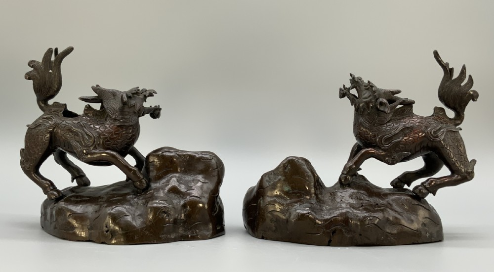 A pair of patinated dark bronze Japanese mythical creature statues positioned on sculpted rocky bases. View VII