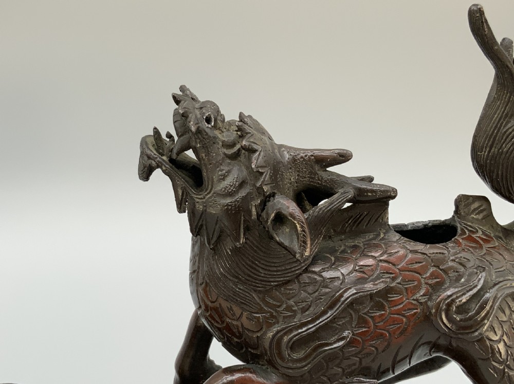 A pair of patinated dark bronze Japanese mythical creature statues positioned on sculpted rocky bases. View VIII
