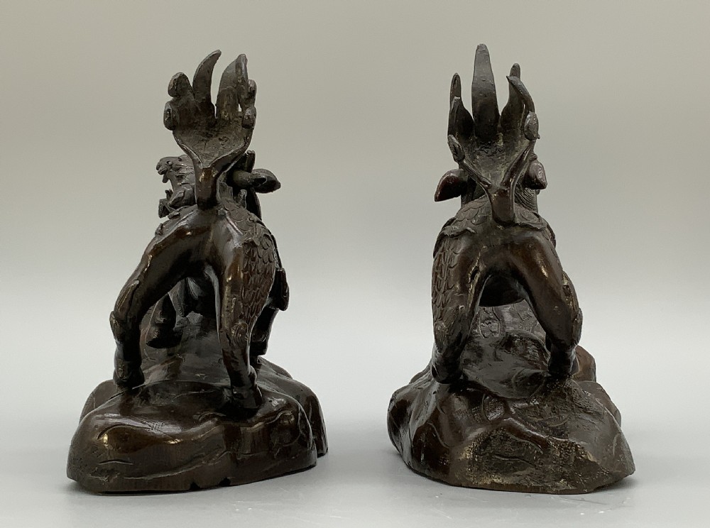 A pair of patinated dark bronze Japanese mythical creature statues positioned on sculpted rocky bases. View XI