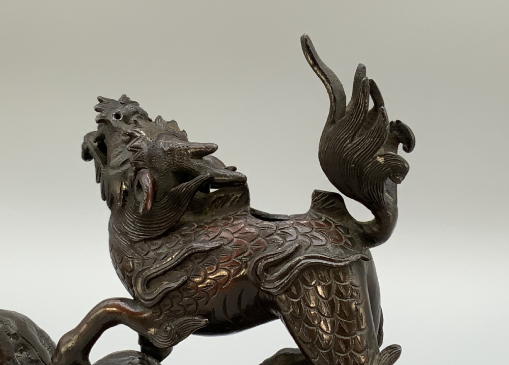 A pair of patinated dark bronze Japanese mythical creature statues positioned on sculpted rocky bases. View XVI