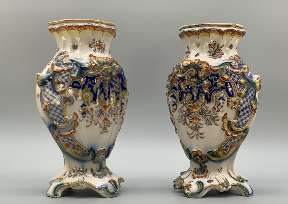 A pair of ornate French faience lidded vases decorated with hand-painted polychrome florals, Rococo scrollwork moulding, and sculptural parrot finials. View XIII