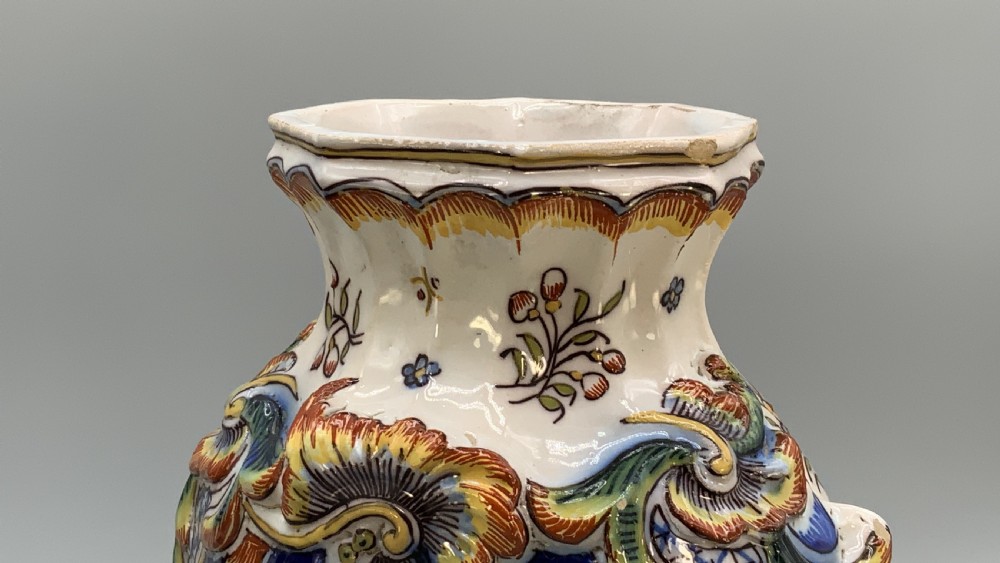 A pair of ornate French faience lidded vases decorated with hand-painted polychrome florals, Rococo scrollwork moulding, and sculptural parrot finials. View XIV