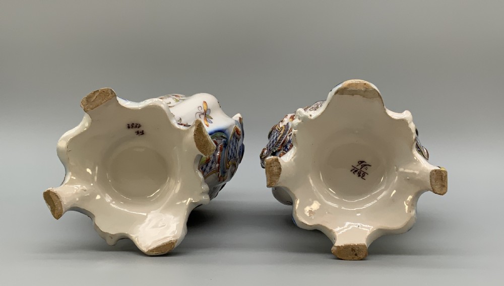 A pair of ornate French faience lidded vases decorated with hand-painted polychrome florals, Rococo scrollwork moulding, and sculptural parrot finials. View XVII