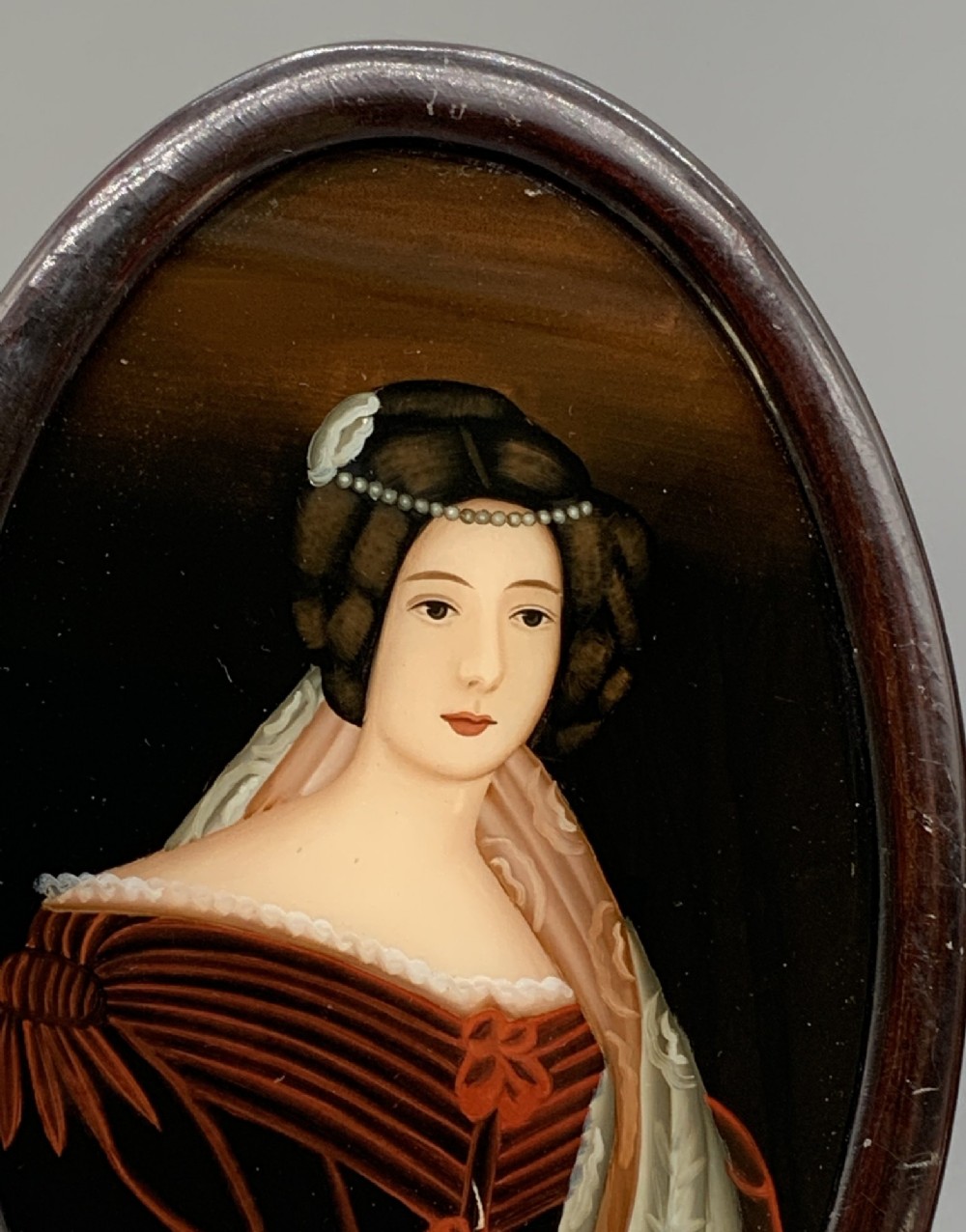 A pair of Japanese Meiji period miniature portrait paintings in oval dark rosewood frames, depicting women in 19th-century style dresses. View VII