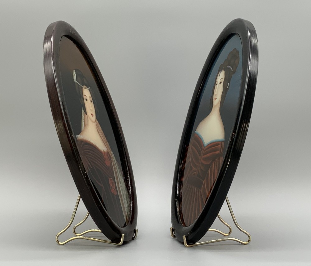 A pair of Japanese Meiji period miniature portrait paintings in oval dark rosewood frames, depicting women in 19th-century style dresses. View IX