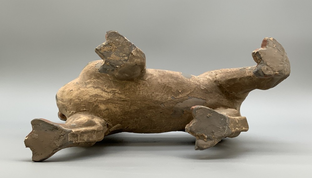 A painted earthenware figure of a tiger-like mythical beast from the Han Dynasty featuring an arched neck, raised tail, and red and green painted stripes. View XV