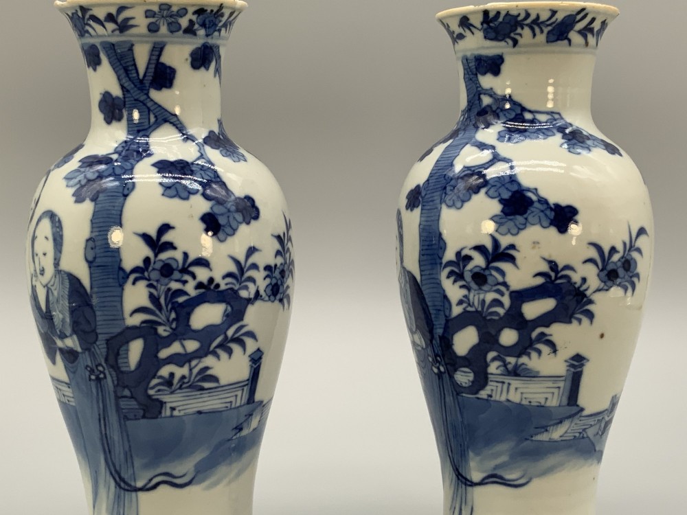 A pair of flared Chinese blue and white porcelain vases hand painted with figural court ladies amidst floral motifs. View VI