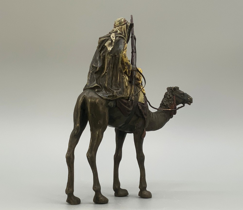 An Austrian cold-painted bronze sculpture depicting a turbaned Arab rider holding a rifle while seated atop a standing camel. View VII