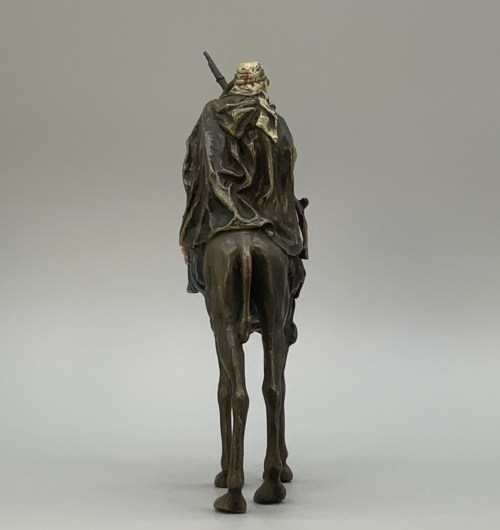 An Austrian cold-painted bronze sculpture depicting a turbaned Arab rider holding a rifle while seated atop a standing camel. View VIII
