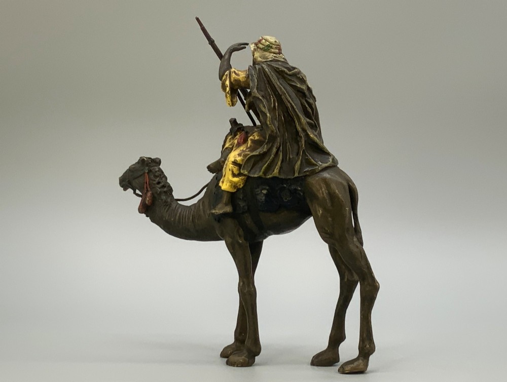 An Austrian cold-painted bronze sculpture depicting a turbaned Arab rider holding a rifle while seated atop a standing camel. View IX