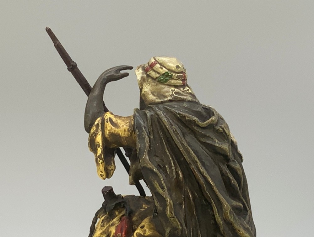 An Austrian cold-painted bronze sculpture depicting a turbaned Arab rider holding a rifle while seated atop a standing camel. View X