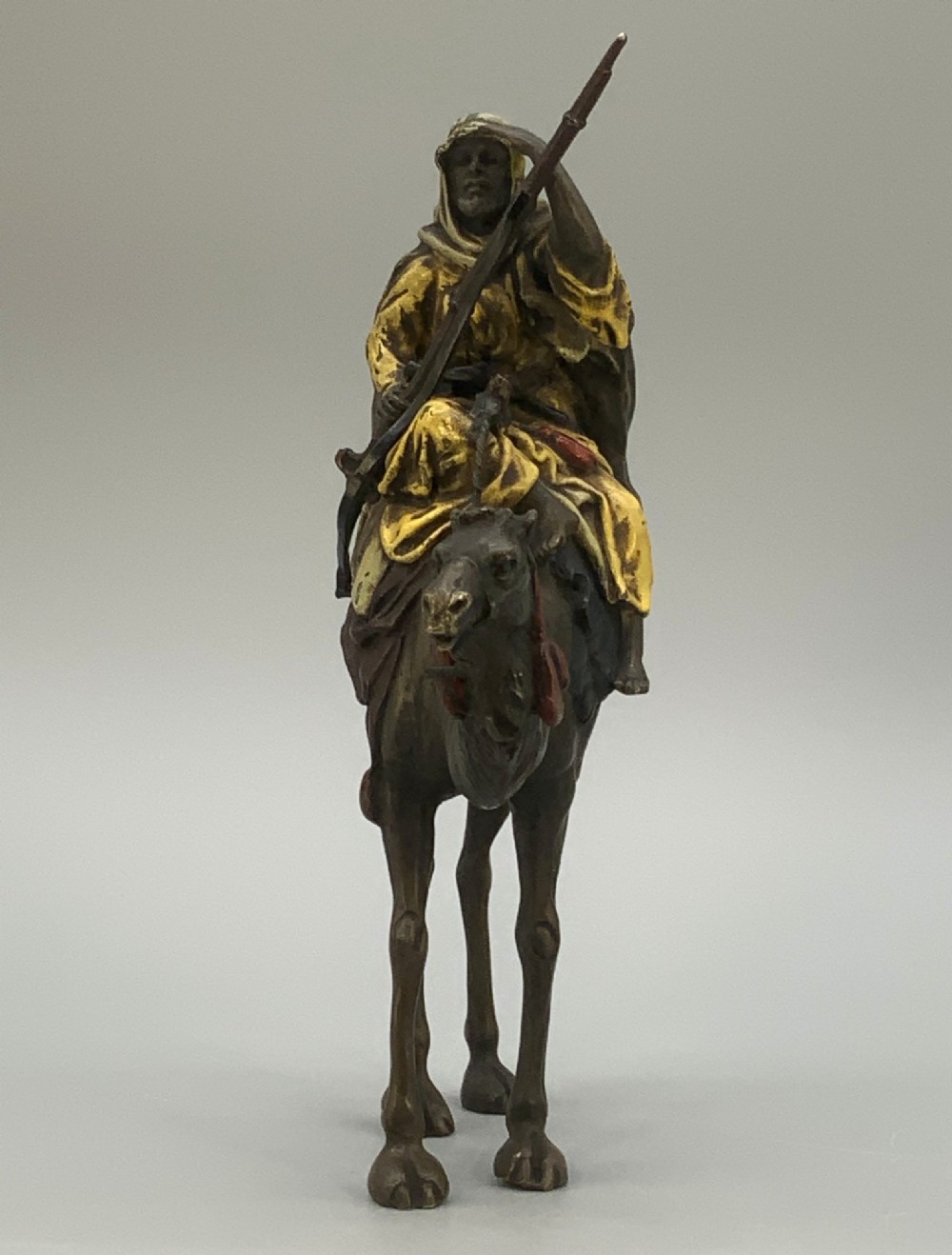 An Austrian cold-painted bronze sculpture depicting a turbaned Arab rider holding a rifle while seated atop a standing camel. View XI