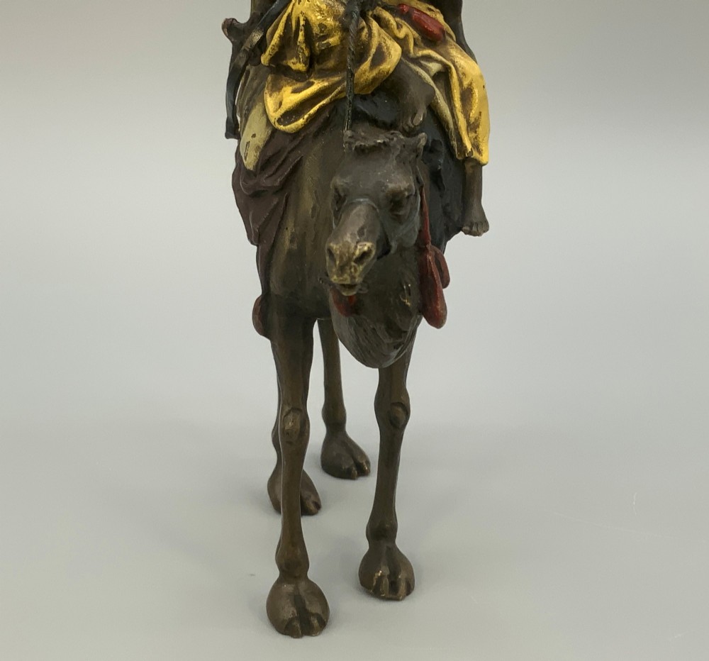 An Austrian cold-painted bronze sculpture depicting a turbaned Arab rider holding a rifle while seated atop a standing camel. View XIII