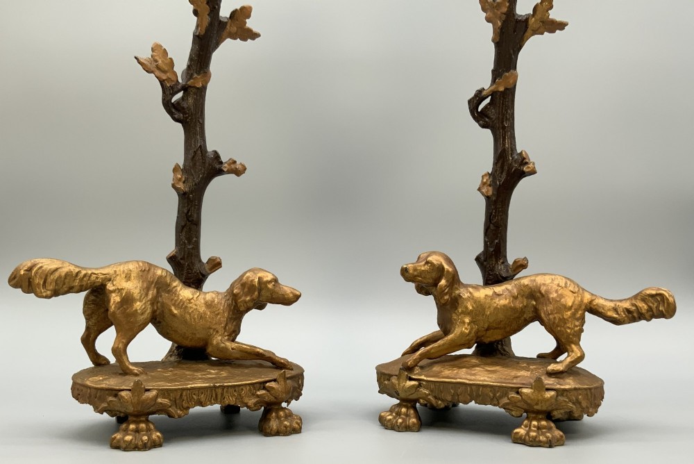 A pair of 19th-century gilded and patinated bronze candlesticks featuring detailed figures of hunting dogs at the base beneath tree-branch shafts. View IV