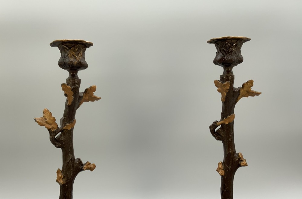 A pair of 19th-century gilded and patinated bronze candlesticks featuring detailed figures of hunting dogs at the base beneath tree-branch shafts. View V