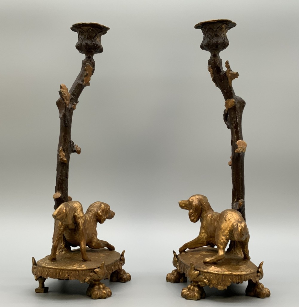 A pair of 19th-century gilded and patinated bronze candlesticks featuring detailed figures of hunting dogs at the base beneath tree-branch shafts. View VI