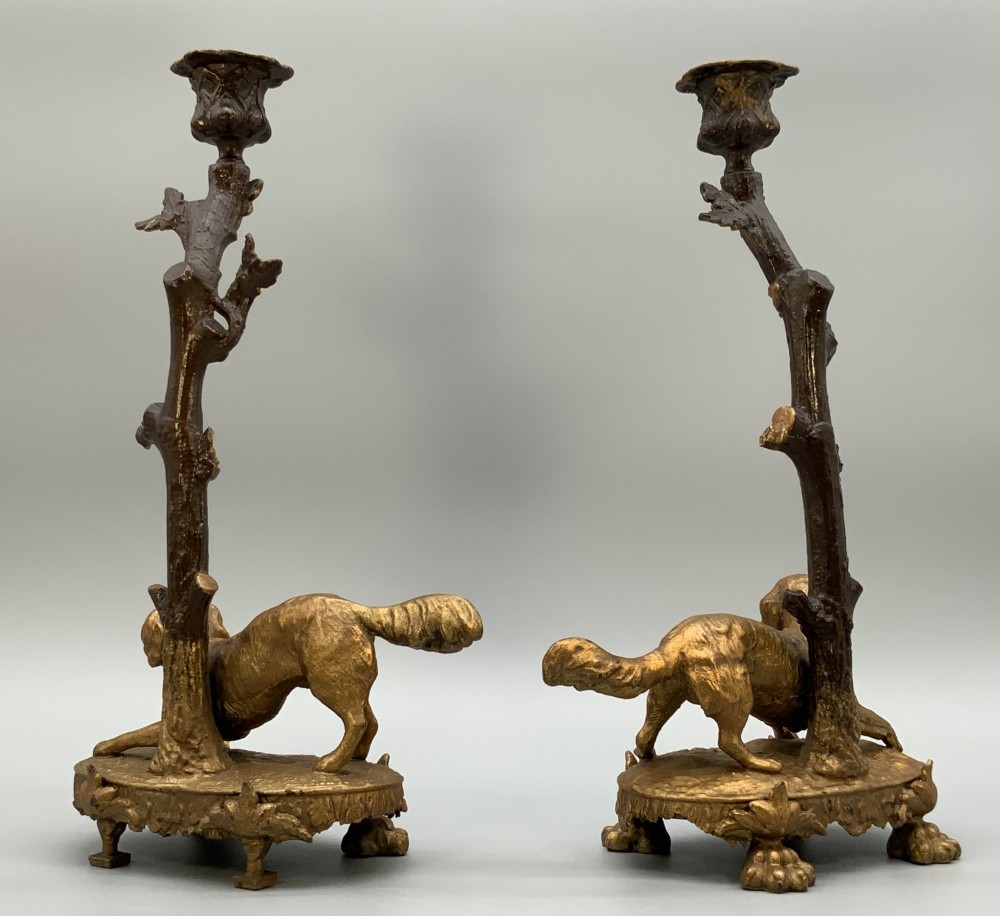 A pair of 19th-century gilded and patinated bronze candlesticks featuring detailed figures of hunting dogs at the base beneath tree-branch shafts. View VII