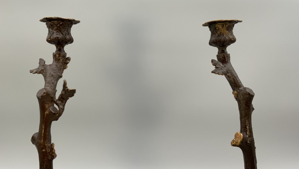 A pair of 19th-century gilded and patinated bronze candlesticks featuring detailed figures of hunting dogs at the base beneath tree-branch shafts. View IX
