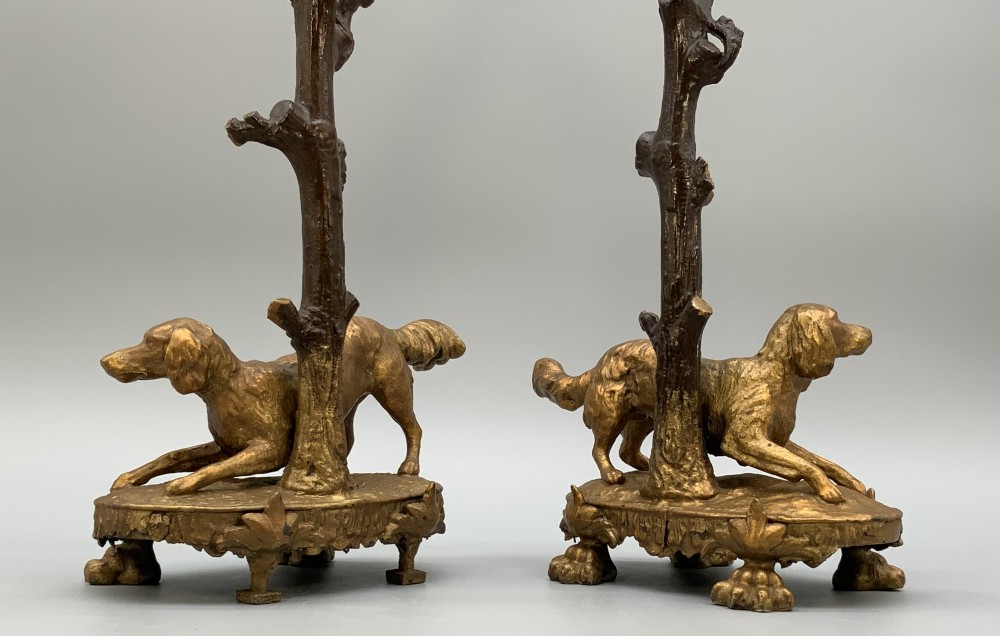 A pair of 19th-century gilded and patinated bronze candlesticks featuring detailed figures of hunting dogs at the base beneath tree-branch shafts. View XI