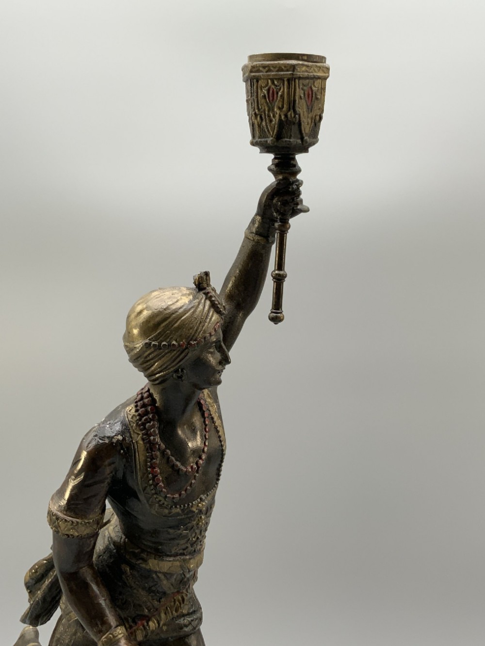 A pair of 19th-century polychrome spelter figural candlesticks depicting male and female torchbearer figures raised on carved wooden bases. View V