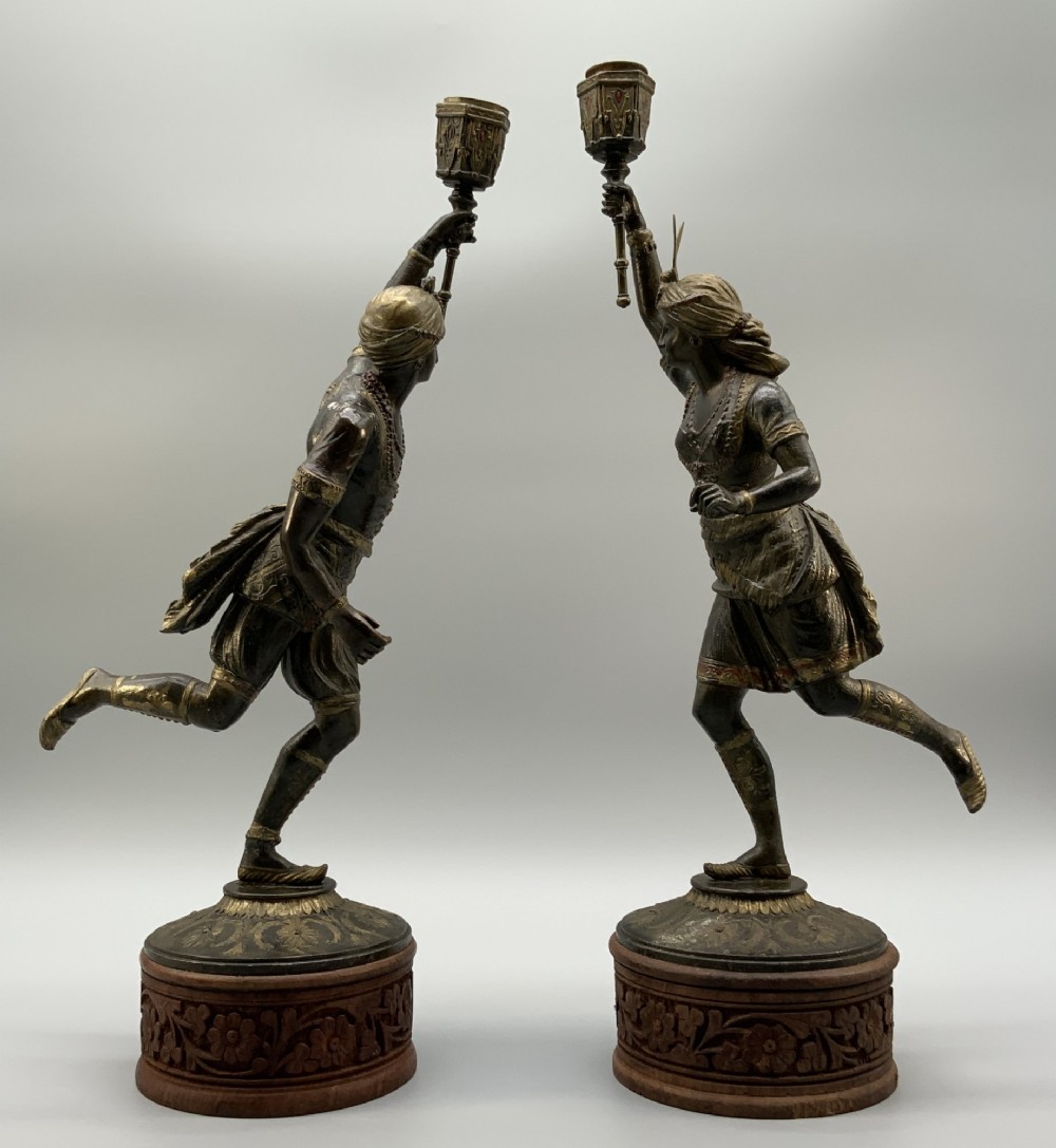 A pair of 19th-century polychrome spelter figural candlesticks depicting male and female torchbearer figures raised on carved wooden bases. View XI