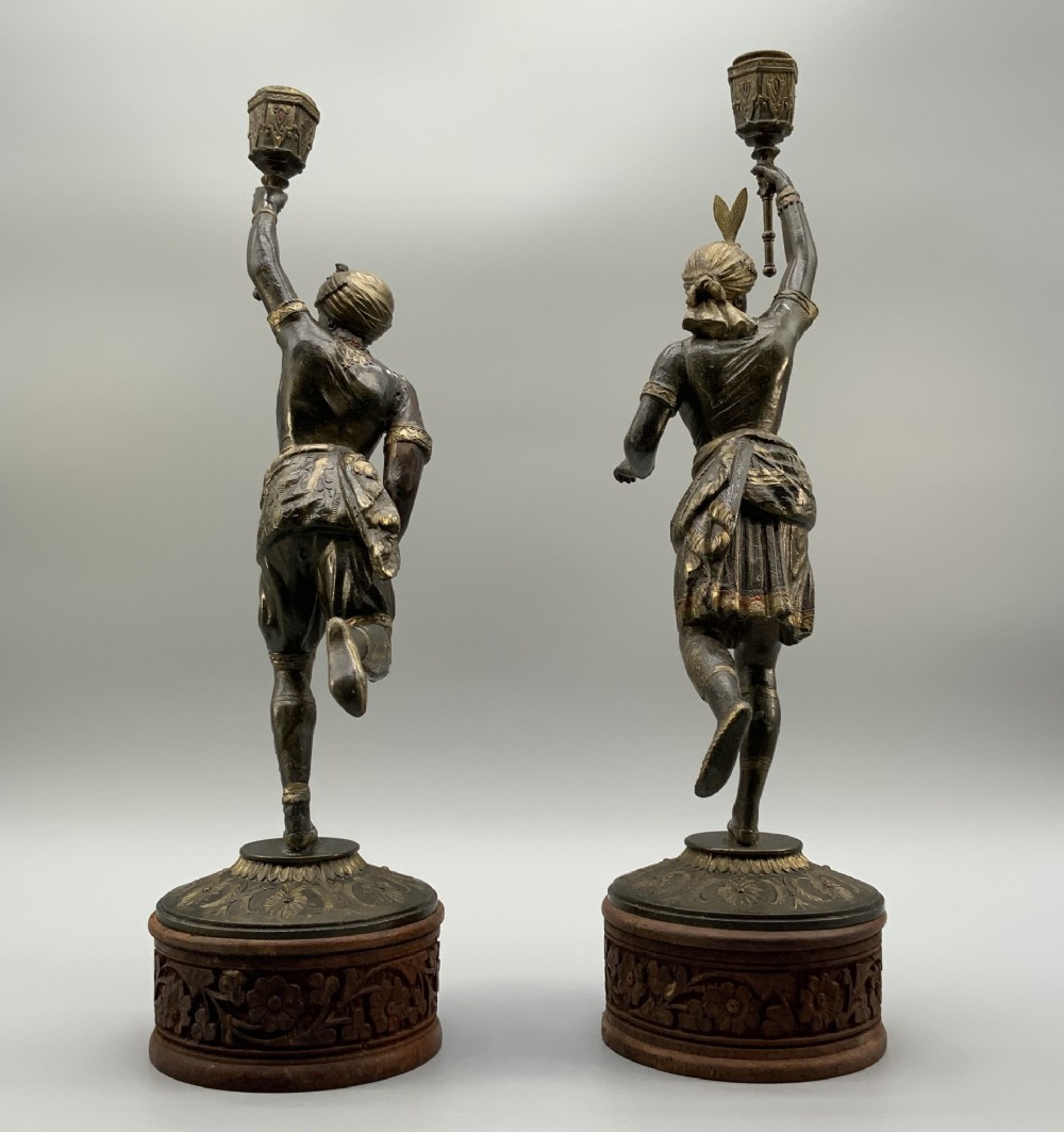 A pair of 19th-century polychrome spelter figural candlesticks depicting male and female torchbearer figures raised on carved wooden bases. View XII