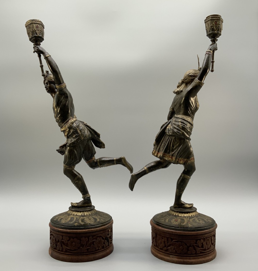 A pair of 19th-century polychrome spelter figural candlesticks depicting male and female torchbearer figures raised on carved wooden bases. View XIII