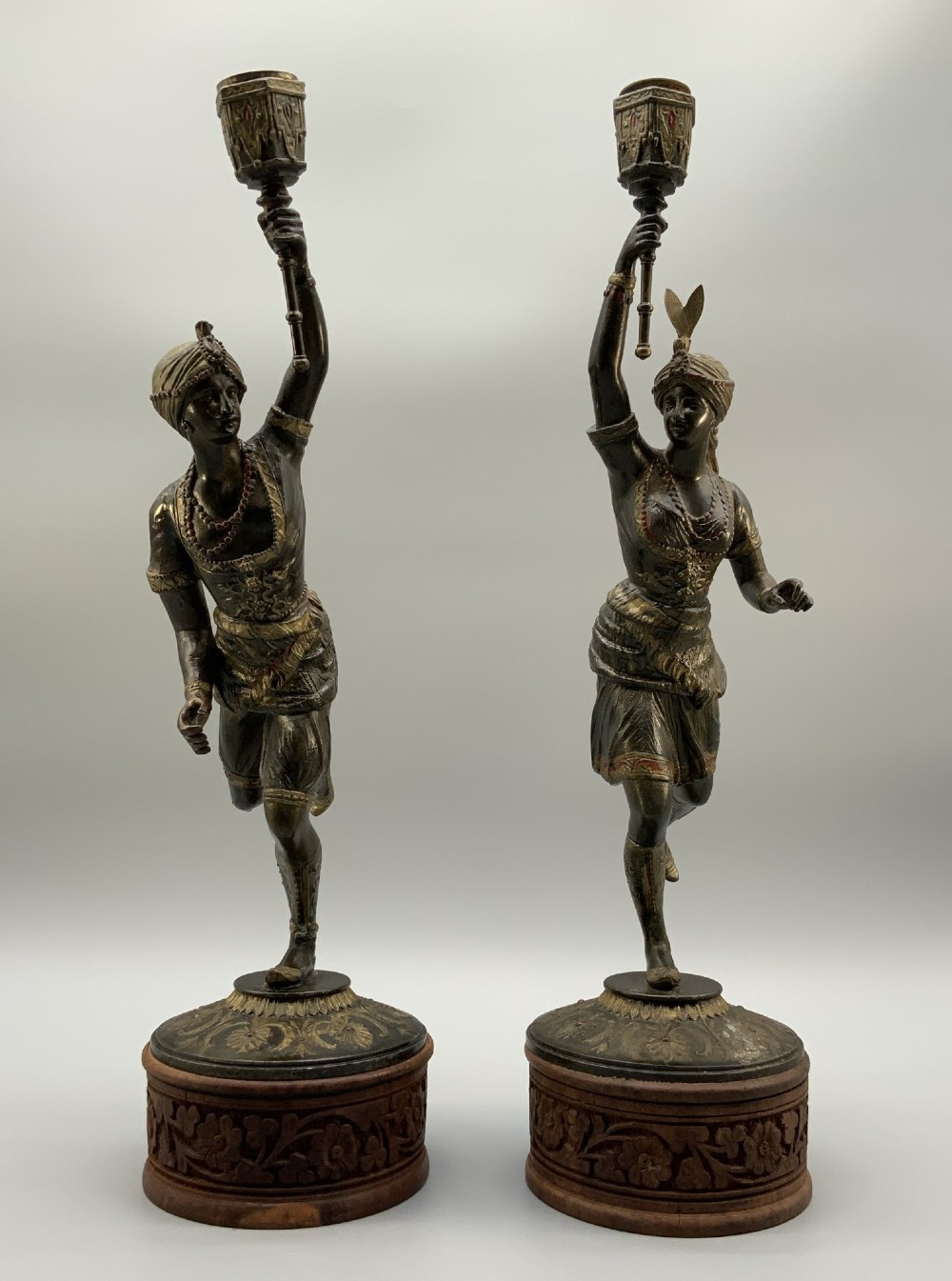 A pair of 19th-century polychrome spelter figural candlesticks depicting male and female torchbearer figures raised on carved wooden bases. View XIV