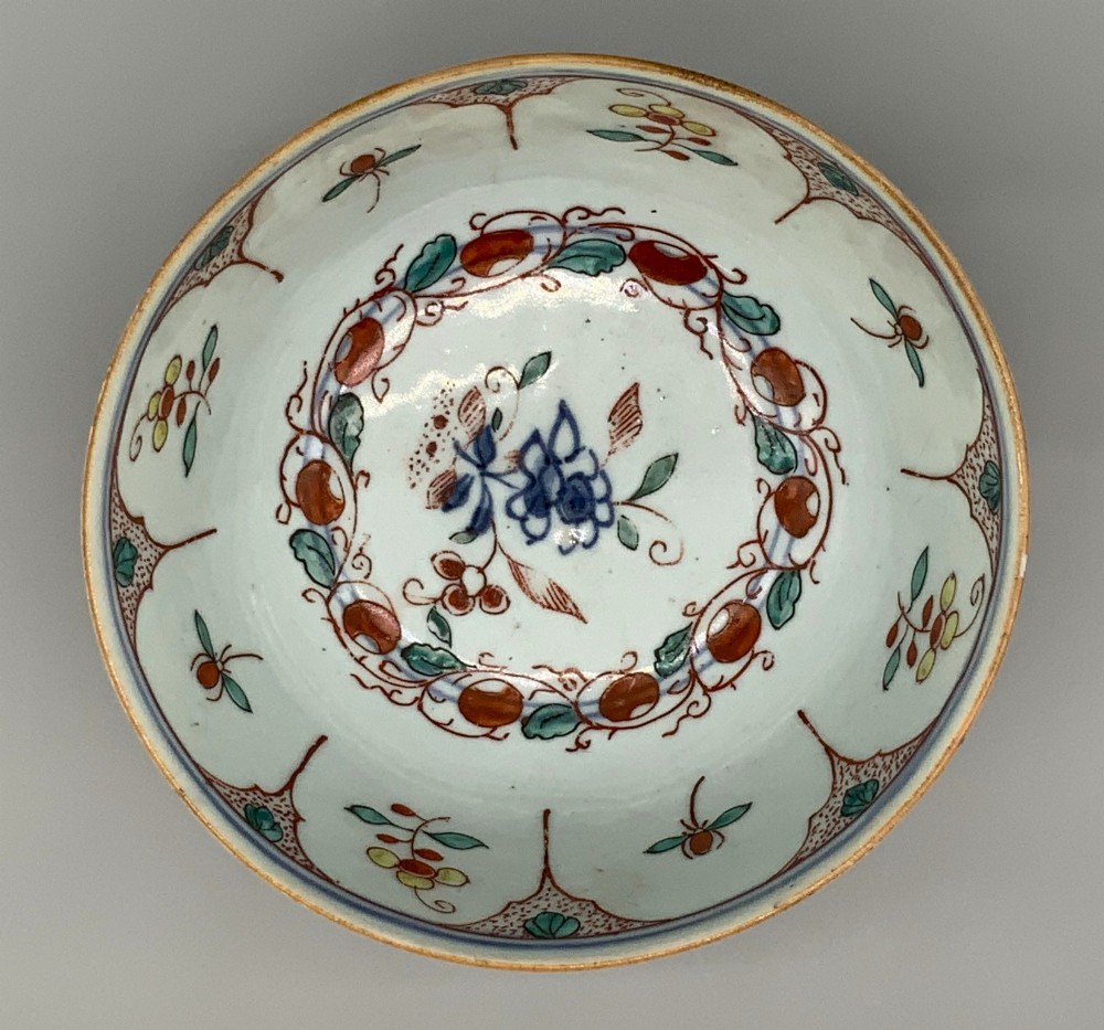 An antique deep circular porcelain bowl featuring hand-painted Chinese Imari floral foliage and diaper pattern borders in blue, red, and green. View IV
