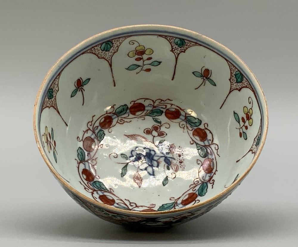 An antique deep circular porcelain bowl featuring hand-painted Chinese Imari floral foliage and diaper pattern borders in blue, red, and green. View VII