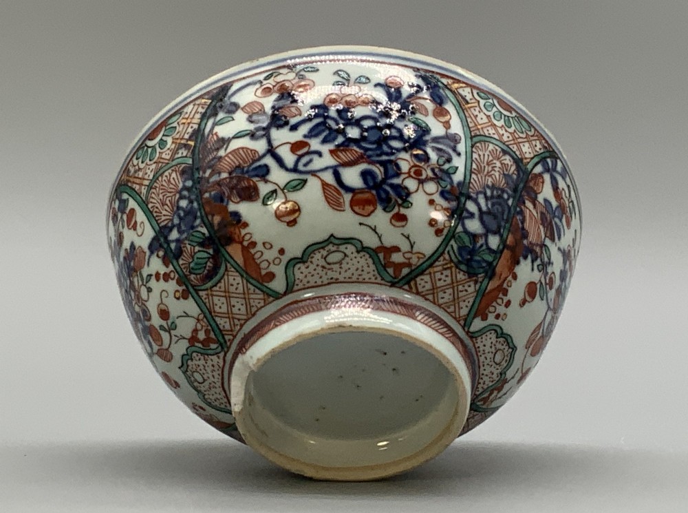 An antique deep circular porcelain bowl featuring hand-painted Chinese Imari floral foliage and diaper pattern borders in blue, red, and green. View VIII