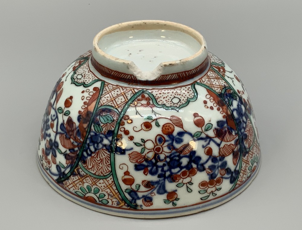 An antique deep circular porcelain bowl featuring hand-painted Chinese Imari floral foliage and diaper pattern borders in blue, red, and green. View IX